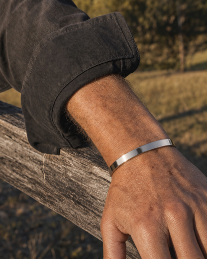 887Seven Meridian Cuff in polished 316L steel, 6mm flat band, worn outdoors with a forearm on a fence rail