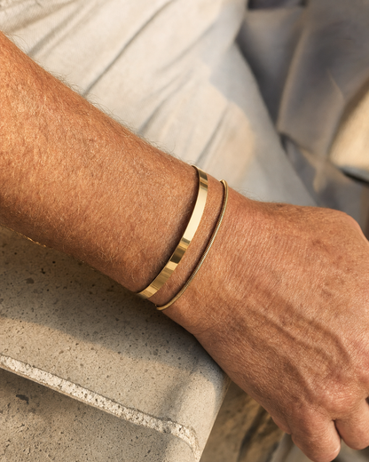 Meridian Cuff Gold worn alongside a gold snake chain bracelet