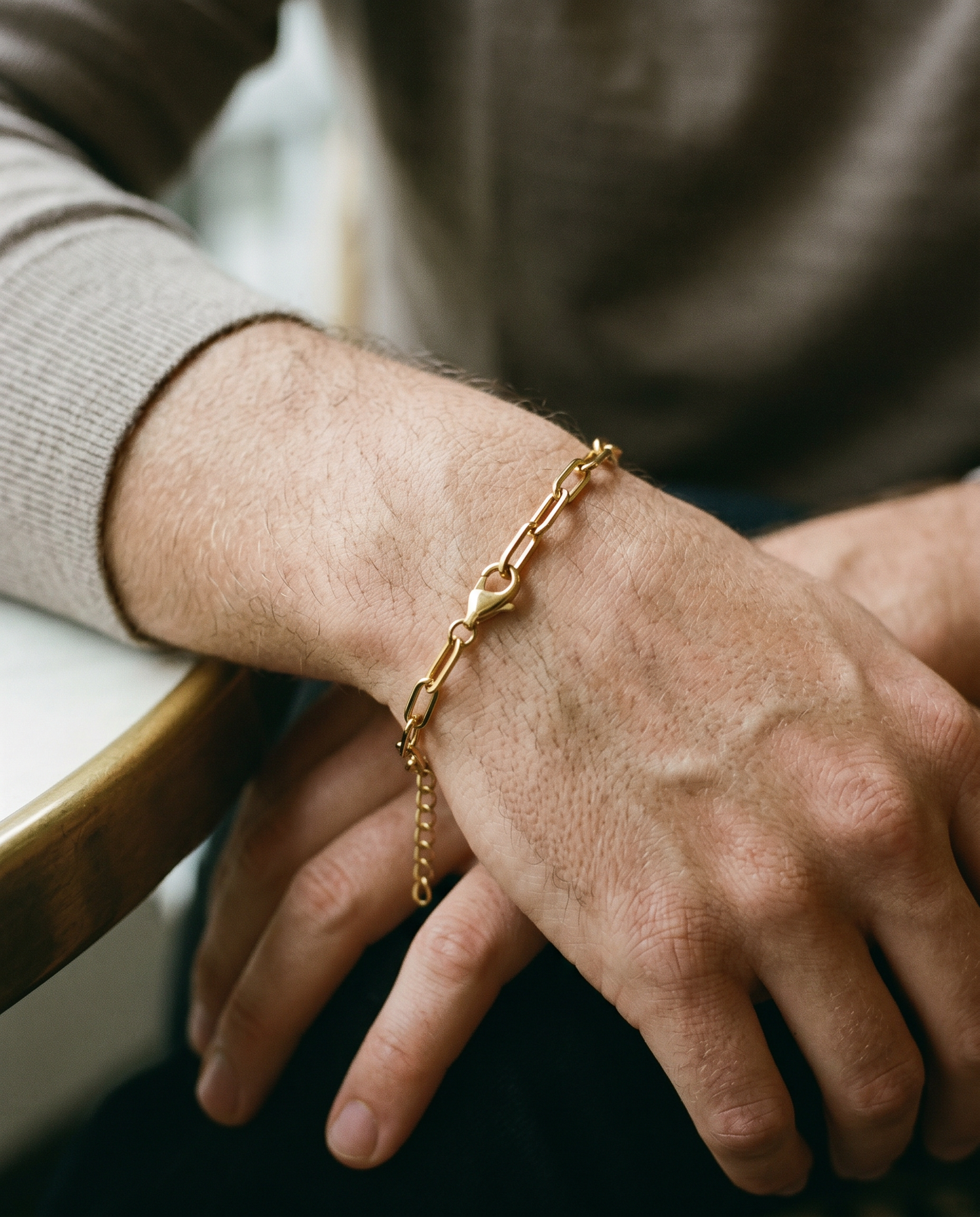 Gold paperclip chain bracelet worn on the wrist